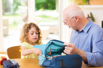 Grandfather and grandson are packing a backpack for school