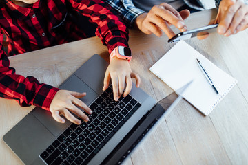Close up photo,  man hands with phone with his granddaughter using laptop for play game.