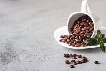 Coffee cup with roasted coffee beans on grey stone background. Copy space for text.