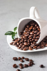 Coffee cup with roasted coffee beans on grey stone background. Copy space for text.