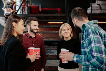 In a modern office center group of multiethnic workers while have a coffee break have a friendly conversation smiling and enjoying the coffee