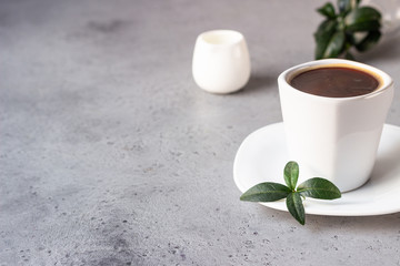 Coffee cup, coffee beans and milk jug on grey stone background. Copy space for text.