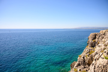 view of Syracuse in the distance from the sea with rocks in the foreground