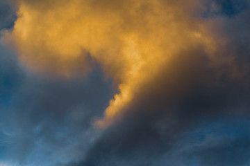 Fluffy clouds illuminated by disappearing rays at sunset and dark thunderclouds floating across sunny blue sky to change season weather. Amazing view natural meteorology background.