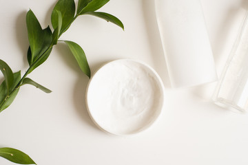 Means for skin care, rejuvenation and hydration of the face. Cream, micellar water and moisturizing lotion on a white background with a branch of green . The philosophy of self care and skin care