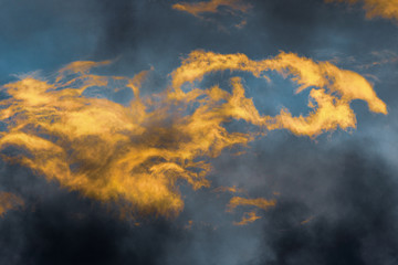 Fluffy thunderstorm clouds illuminated by disappearing rays at sunset and dark thunderclouds floating across sunny blue sky to change season weather. Stunning view natural meteorology background.