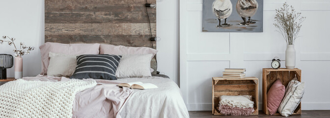 Panoramic view of trendy bedroom in rustic style with wooden boxes as nightstand tables