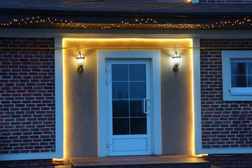 white glass door on a brown brick wall with lanterns and yellow lighting on a night street