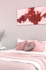 King size bed with pastel pink and white bedding in trendy bedroom interior