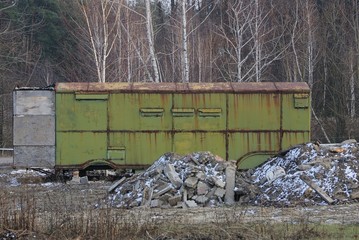 one old green iron container in rust stands on the street near heaps of garbage in the snow on a winter day