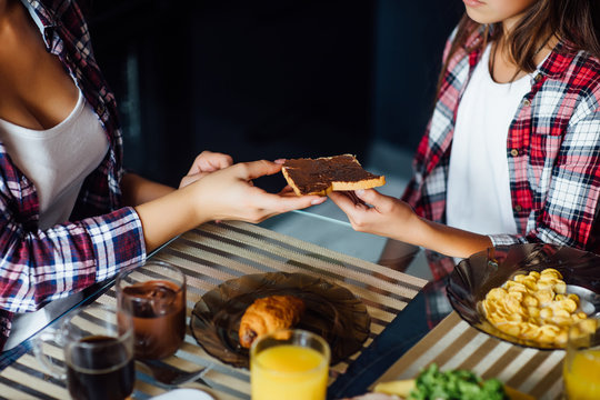 Cropped image, girls have a breakfast with flakes and bread spread with chocolate.