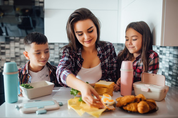 Mother making breakfast for her children in the morning and a snack with lunch box for school.