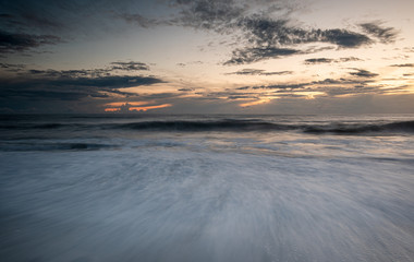 Seawaves splashing on the coast during a dramatic sunset