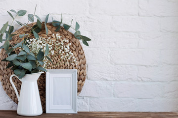 Obraz premium vase with flowers and a photo frame at home on a wooden table.