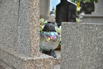 Samotny znicz wśród grobowców na cmentarzu w pochmurny dzień.