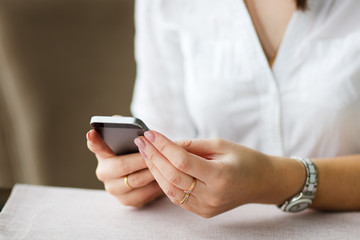 business woman in cafe smiles and writes sms phone