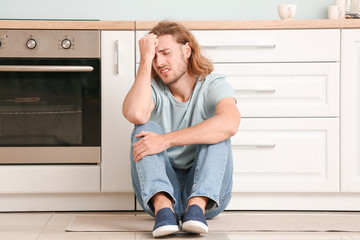 Depressed man in kitchen at home