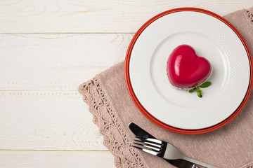 Dessert mousse in the shape of a pink glazed heart with a rose, for Valentine's Day. Flat lay