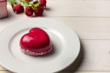 Dessert mousse in the shape of a pink glazed heart with a rose, for Valentine's Day.