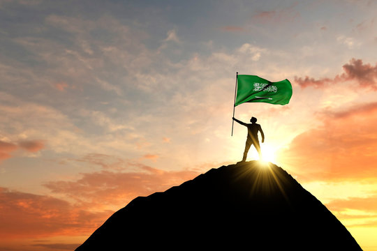 Saudi Arabia flag being waved at the top of a mountain summit. 3D Rendering