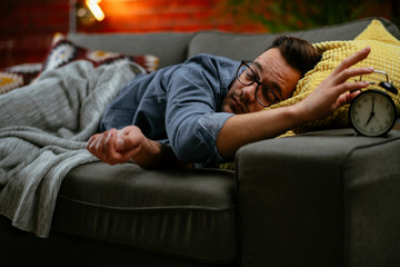 Young man sleeping on couch. Tired man fell asleep in living room. 