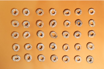 Bublik cookies pattern. Ring shaped roll cookies on orange background.. - obrazy, fototapety, plakaty