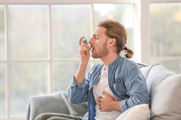 Sick man with asthma inhaler at home
