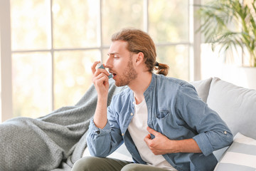 Sick man with asthma inhaler at home