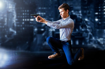Man in shirt and jeans pointing gun, armed robbery against the background of the night city,...