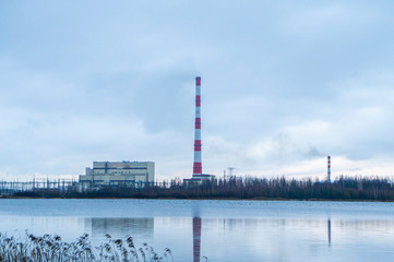 Red-white factory chimney near a winter lake.