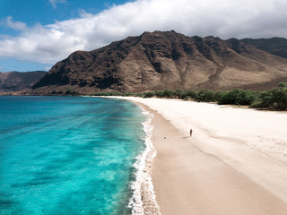 Man walking on the beach - Tropical paradise beach with white sand and mountain background travel tourism wide panorama background. Hawaiian beach. Oahu.