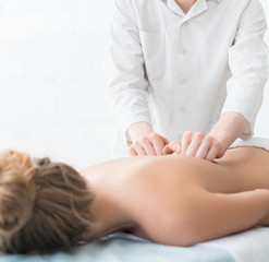 Obraz na płótnie Canvas Handsome massagist making massage to blonde in spa