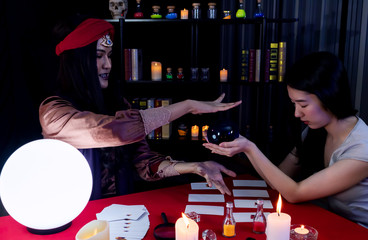 Asian fortune teller is predicting for a female customer.