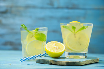 Lemonade or mojito cocktail with lemon and mint on wood background