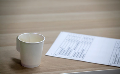 Blank paper coffee mugs resting on a wooden table complete with documents.