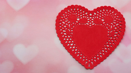 red heart paper doily isolated on a pink and white faded hearts background