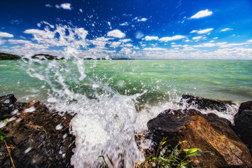 Splashes of water on the shore of Lake Balaton. The waves break on the shore on a windy summer day. 
