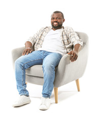 African-American man relaxing in armchair against white background