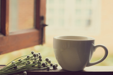 White coffee cup of hot tea or coffee on vintage wooden  with window background
