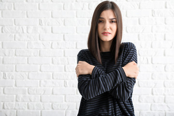 Worried young woman against white brick background