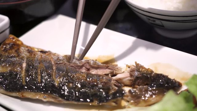 4k Japanese healthy dinner, close up wood chopsticks picking on grilled saba fish, Asian cuisine, nutrition diet, omega 3, green vegetable, meal course dinner, indoor restaurant, East Asian tradition