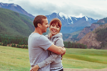 the couple stands against the background of mountains