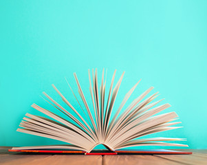 Open book on wooden table on blue background