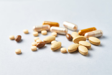 Multicolor vitamins and supplements on bright paper background. Concept for a healthy dietary supplementation. Close up. 