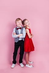 Cute smiling boy and girl standing on a pink background . Valentine's Day.