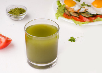 matcha green tea on a white background next to scrambled eggs and vegetables. healthy breakfast concept