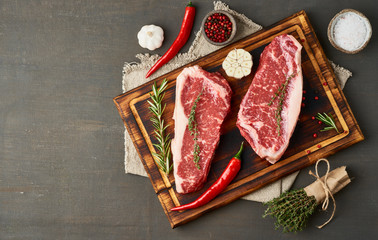 Seasoning raw steak with salt, thyme, garlic. Two big whole piece of raw beef meat