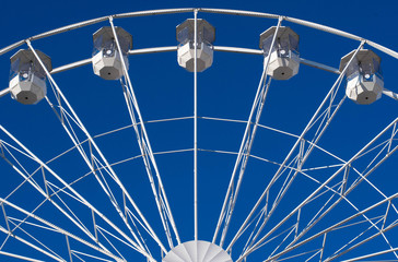 White Ferris wheel against clear blue sky. Fun outside adventure. Symmetric Ferris wheel  
