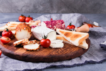 Toasts with tomatoes, goat cheese and basil on a wooden table with a glass of wine.