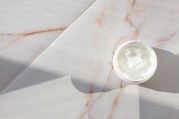 Cream in a jar on marble. Spa layout with text space. Preservation of youth, smoothing wrinkles, skin care